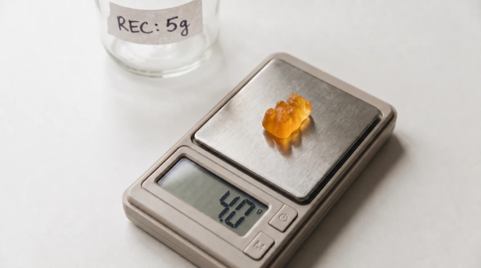 A kitchen scale showing a single gummy weighing less than the label's stated dose.